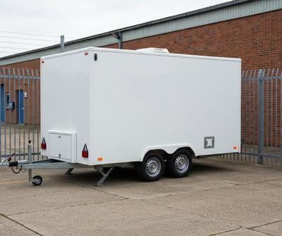 White mobile catering trailer parked in a secure private industrial yard