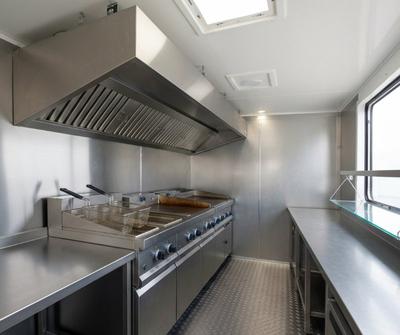 Stainless steel extraction canopy mounted inside a catering unit above the fryers and griddle
