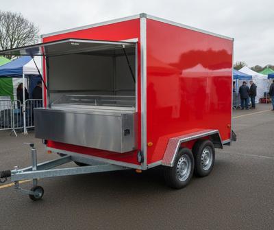 Red jacket potato catering trailer with a stainless steel serving hatch at a UK outdoor market