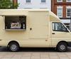 Cream mobile coffee van with a side serving hatch on a UK high street