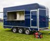 Navy blue converted horsebox catering trailer with a portable generator