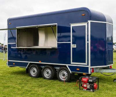 Navy blue converted horsebox catering trailer with a portable generator