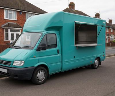 Teal compact catering van with an open side serving hatch parked on a UK residential driveway