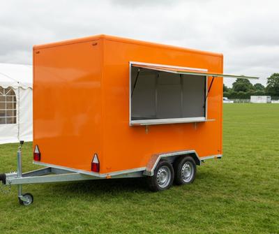 Orange catering trailer with side serving hatch at a UK outdoor sporting event