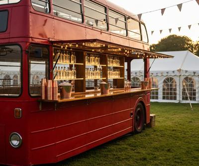 Converted vintage double-decker bus serving as a mobile bar at a UK outdoor event