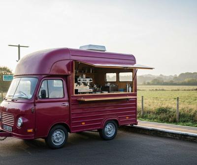 Burgundy vintage mobile coffee van with the side serving hatch open in the British countryside